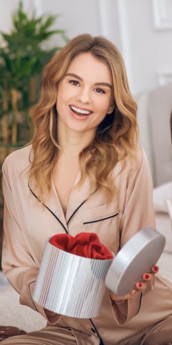 A gift. Three pretty girls in pajamas opening the gift box and looking excited